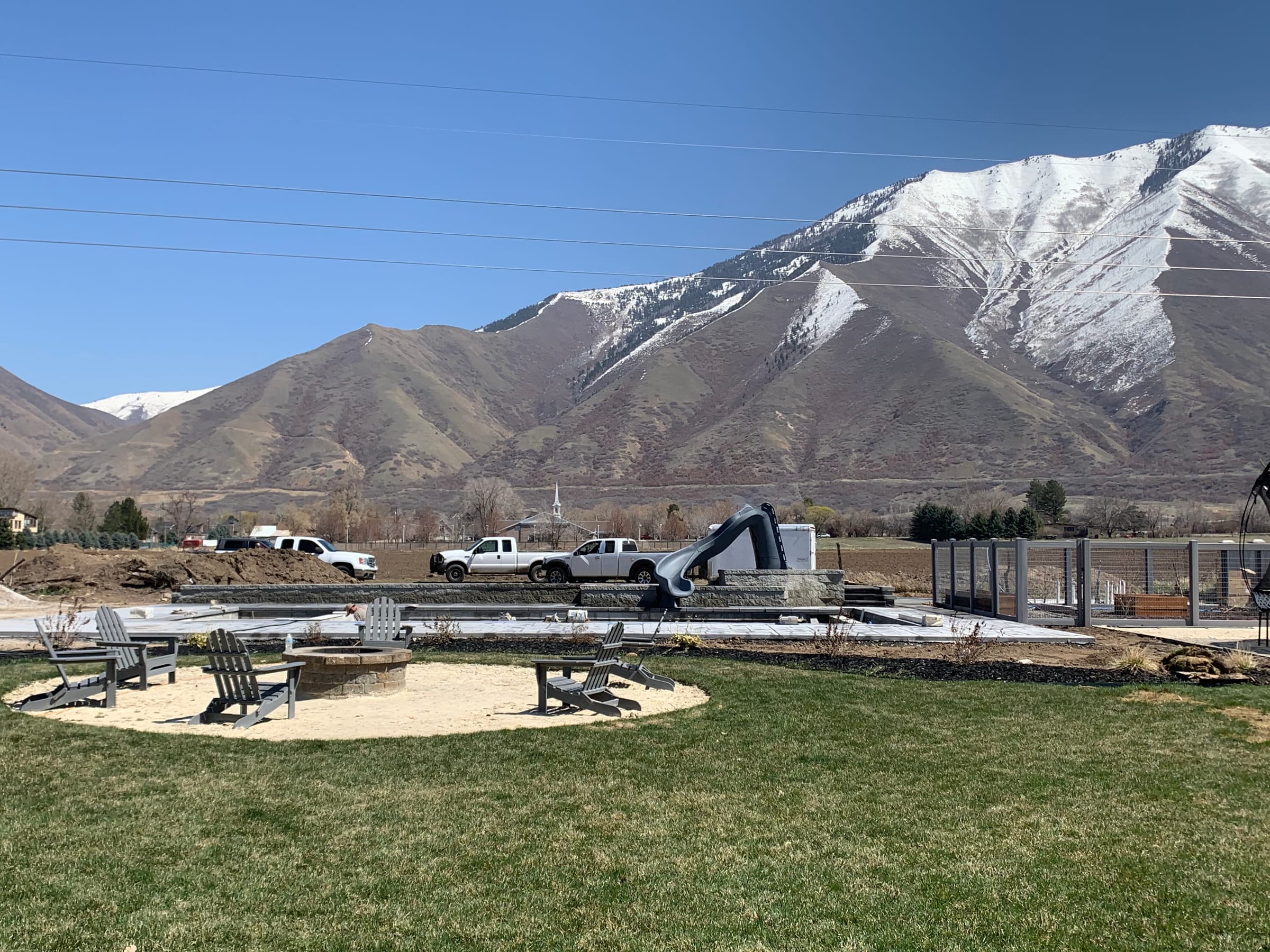 Finished backyard with a fire pit and new lawn below snow-capped Wasatch peaks