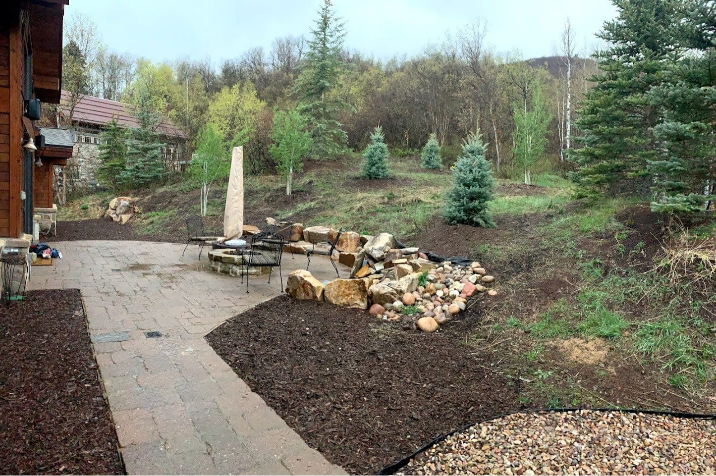 Paver patio beside a boulder dry creek and fire pit